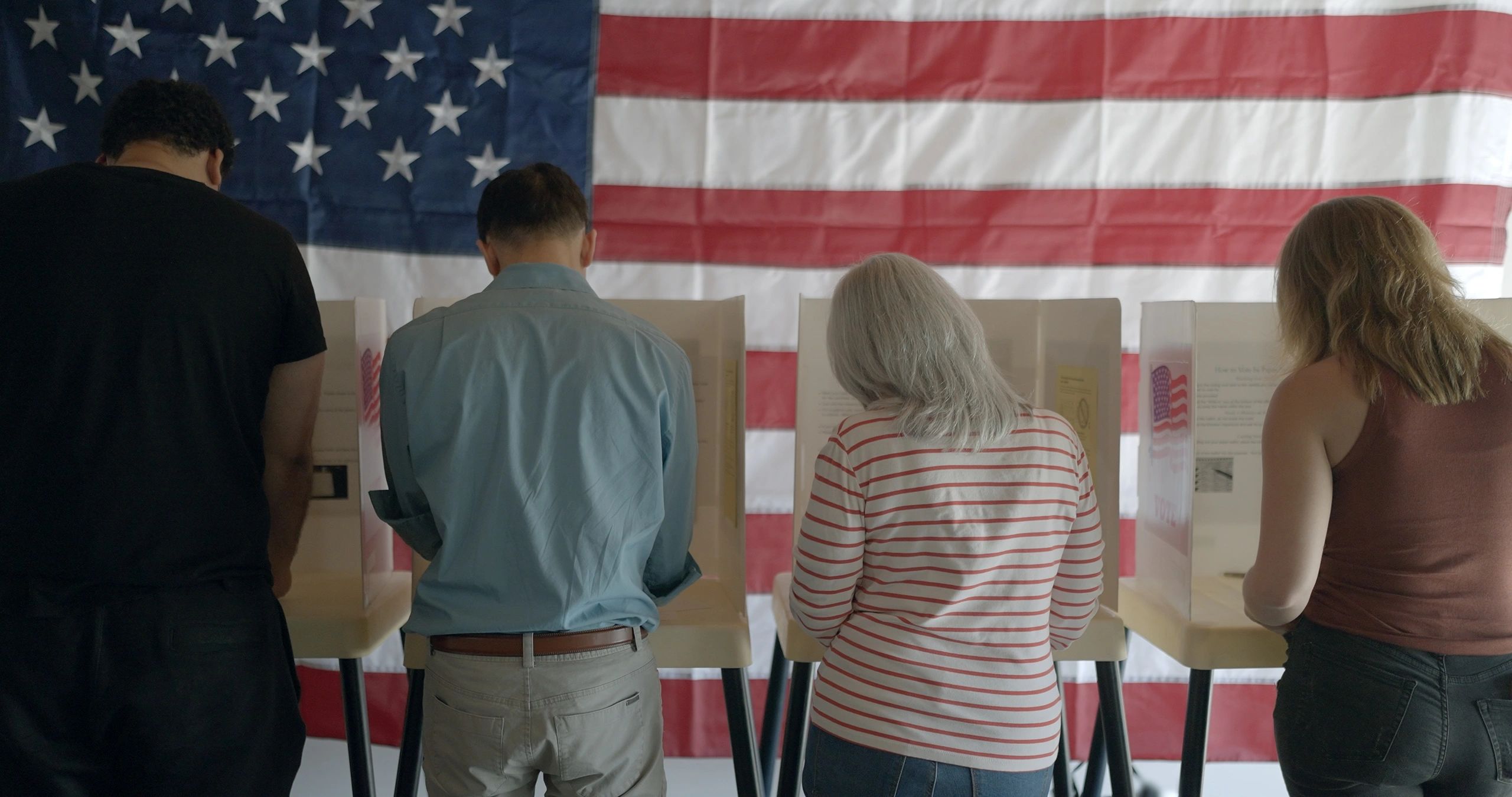 Community members participating in a civic voting event with an American flag in the background